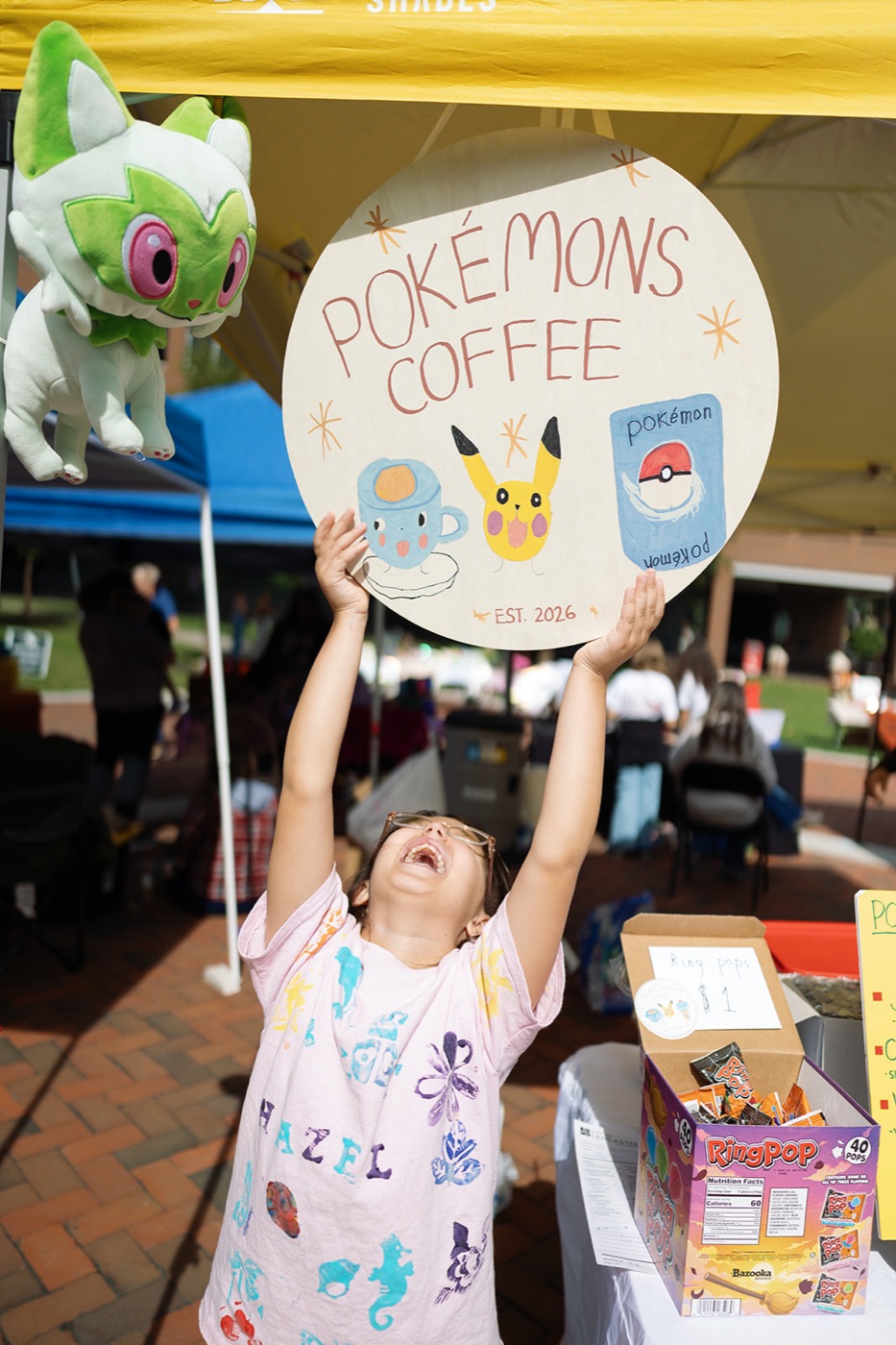 A kid holding the Pokémon Cafe sign over her head
